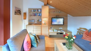 A modern living room with a television, sofa, and bookshelves. - MAC's Apartment - MAC's Apartment (Au)