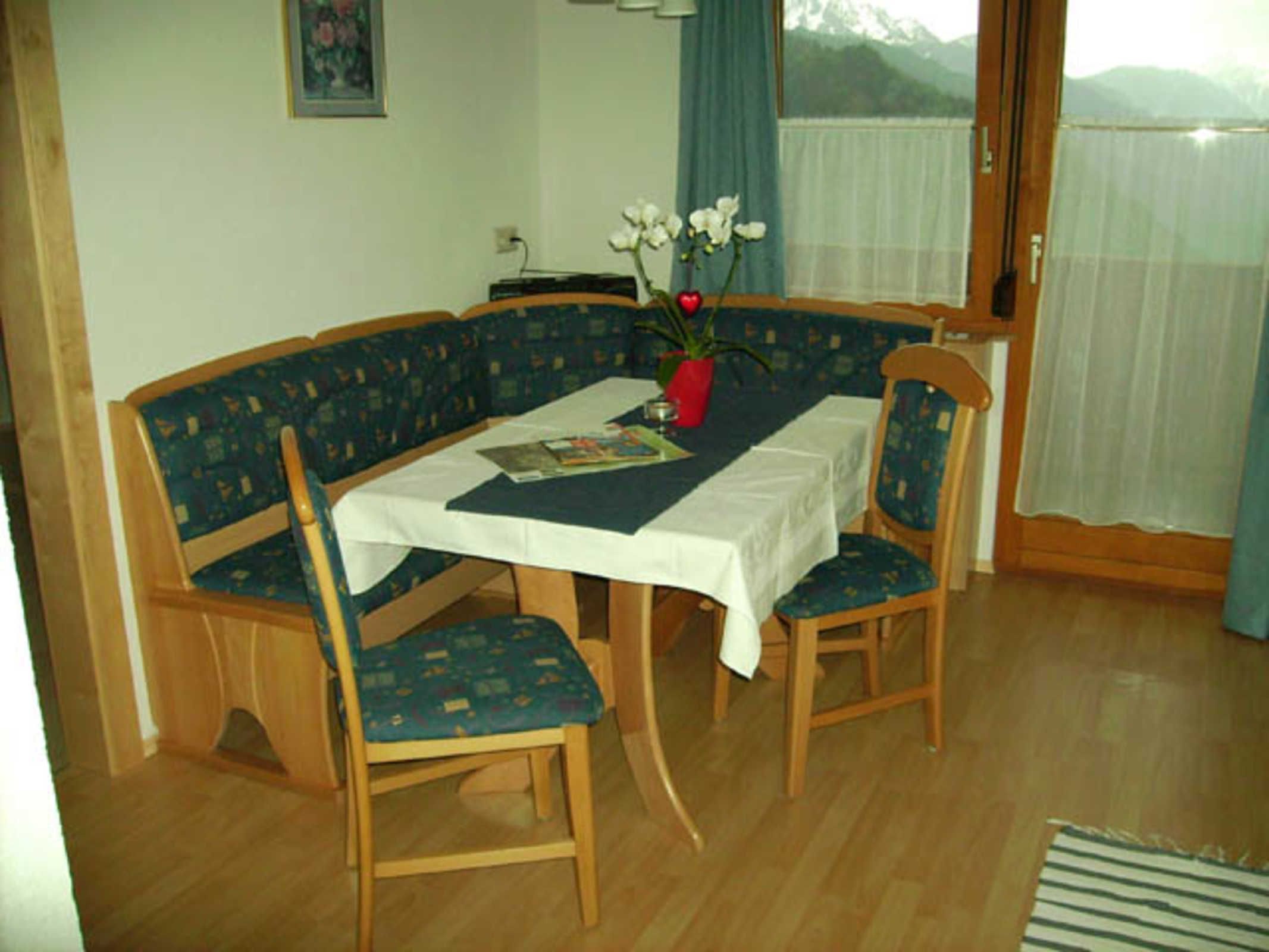 A dining area with a table, chairs, and a vase with flowers.