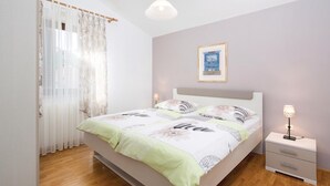 Un dormitorio con cama, mesitas de noche, una lámpara y un cuadro en la pared.