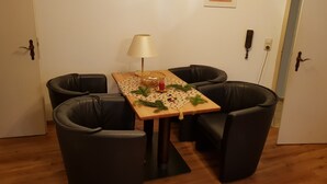 Un comedor con una mesa dispuesta para cuatro personas, rodeada de sillas negras. Una lámpara y un centro de mesa decorativo están sobre la mesa.