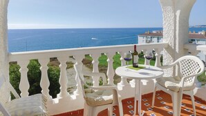 A balcony with a white balustrade, a round table with a chair, and a bottle of wine. - 1 bedroom beach front apartment in Mezquitilla (Mezquitilla)