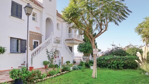 A white building with a staircase, a tree, and a sign indicating a sale. - 1 bedroom beach front apartment in Mezquitilla (Mezquitilla)