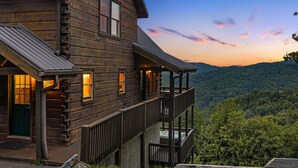 Eine Holzhütte mit Balkon, Treppe und Blick auf den Wald.