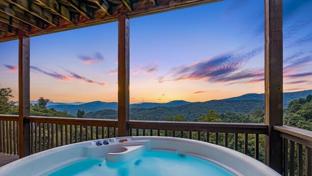 Ein Whirlpool auf einer Holzterrasse mit Blick auf eine schöne Berglandschaft.