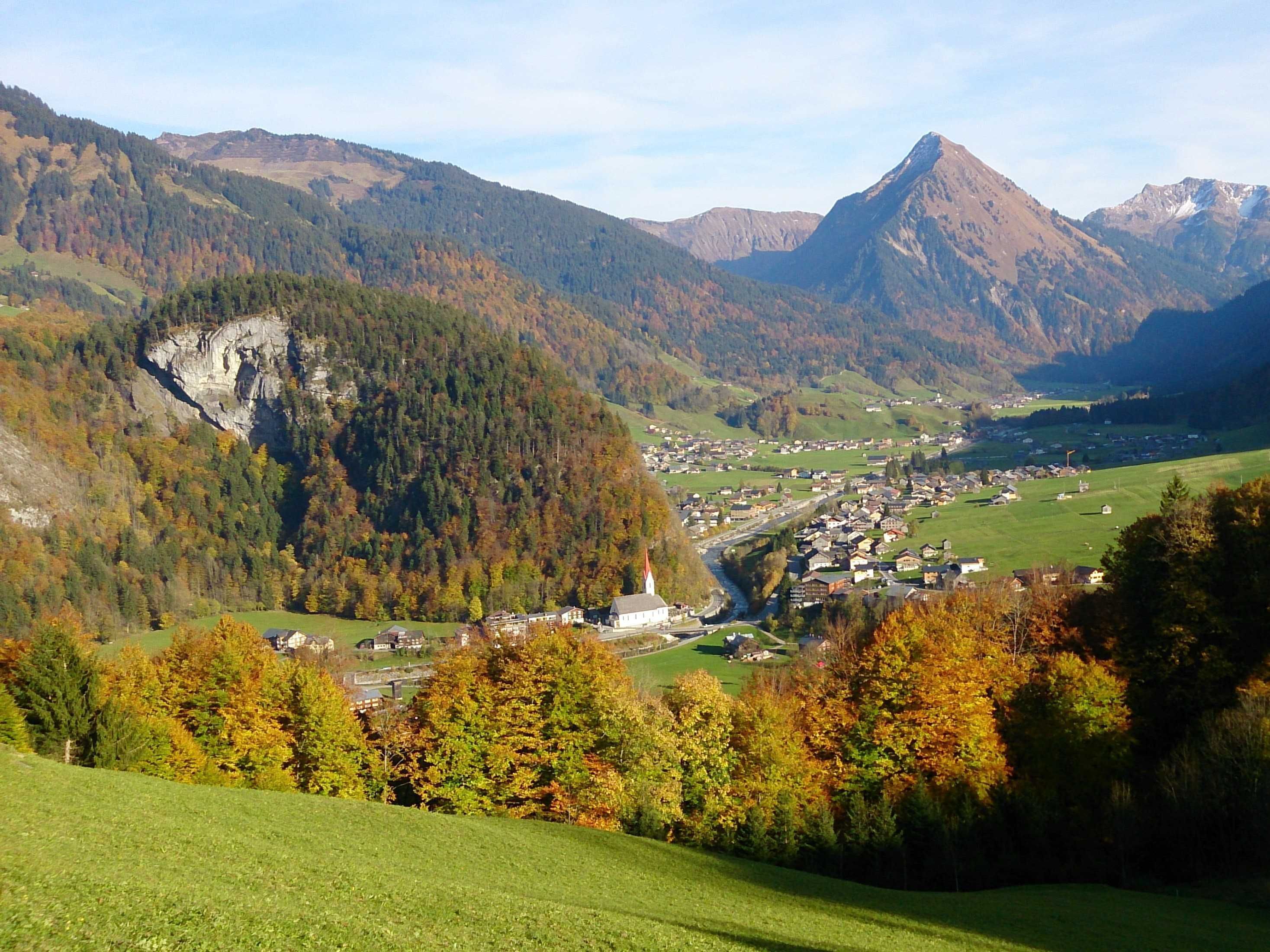 A valley with a town, mountains, and autumn trees.