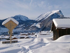 En snötäckt by med trähus och en bergskedja i bakgrunden.