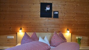 A wooden-paneled room with two beds, each with red and white checkered bedding, white pillows, and wall-mounted lights. - Holiday at Rüf's - Apartment 1 (2-6 people) (Au)