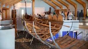 A museum exhibit with a large wooden boat model, informational plaques, and visitors. - Garden Apartment 1 - Ferienhof Schmeling (Ahneby)