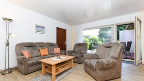 A living room with a sofa, two armchairs, a coffee table, and a floor lamp. - Apartment Seerose - House Ursula (Esens)