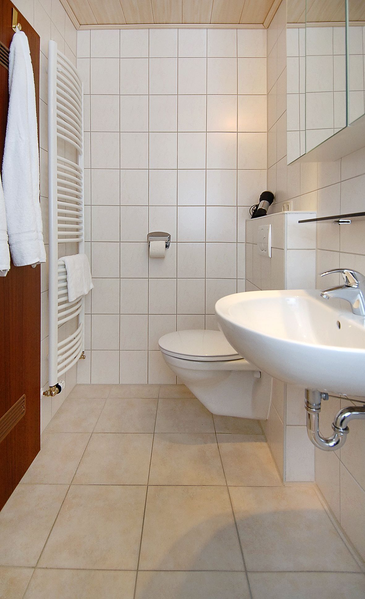 Un bagno con lavandino, water e portasciugamani bianchi.