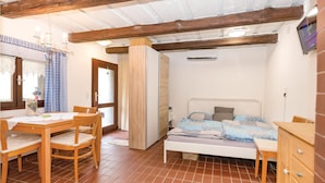 A bedroom with a bed, a wooden dresser, a desk with a chair, and a window with curtains.