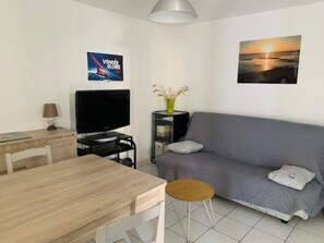 Una sala de estar con televisor, sofá y una mesa de comedor.