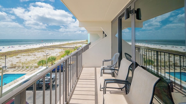 Un balcón con vista a la playa y una piscina.