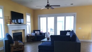 A living room with a fireplace, a television, and a ceiling fan.
