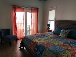 Une chambre à coucher avec un grand lit, une chaise et une fenêtre avec des rideaux.