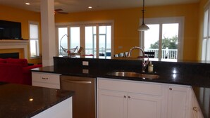 A modern kitchen with a black countertop, white cabinets, a stainless steel sink, and a red chair.