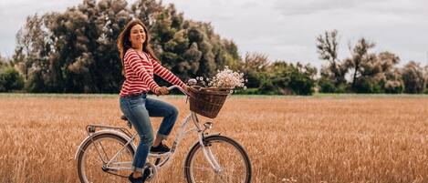 Una persona montando en bicicleta con una cesta por un sendero de tierra a través de un campo.