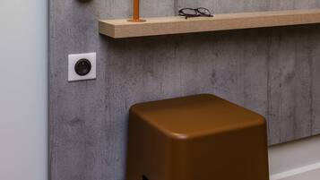 A modern interior with a concrete wall, a wooden shelf, a pair of glasses, and a brown stool.