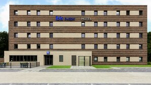 A modern hotel building with a brick facade, multiple windows, and a visible entrance. - Ibis budget Stein Maastricht (Stein)