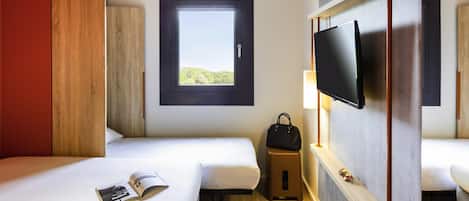 Habitación de hotel con dos camas, ventana con vistas, televisor y un taburete pequeño.
