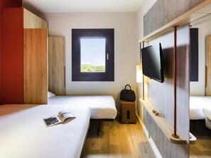 Habitación de hotel con dos camas, ventana con vistas, televisor y un taburete pequeño.