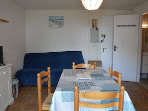En matplats med ett bord dukat för fyra personer, en blå soffa och ett köksområde i bakgrunden.