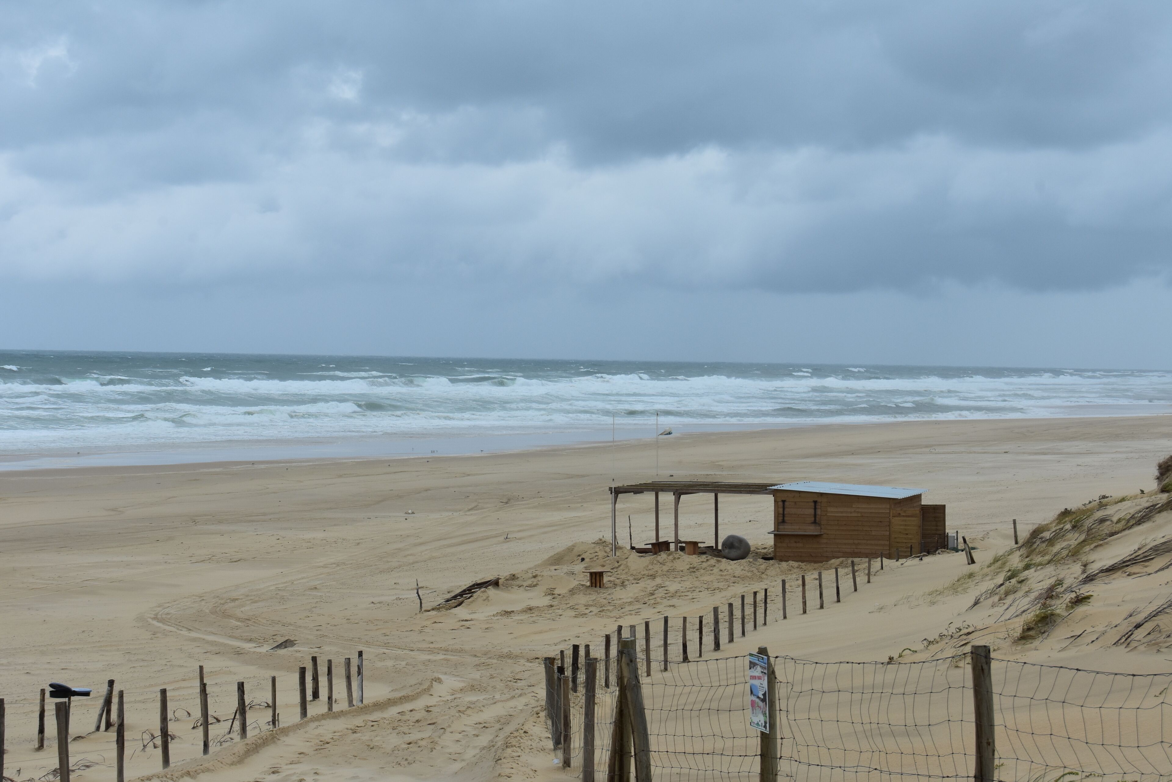 A beach with a wooden structure and a fence.