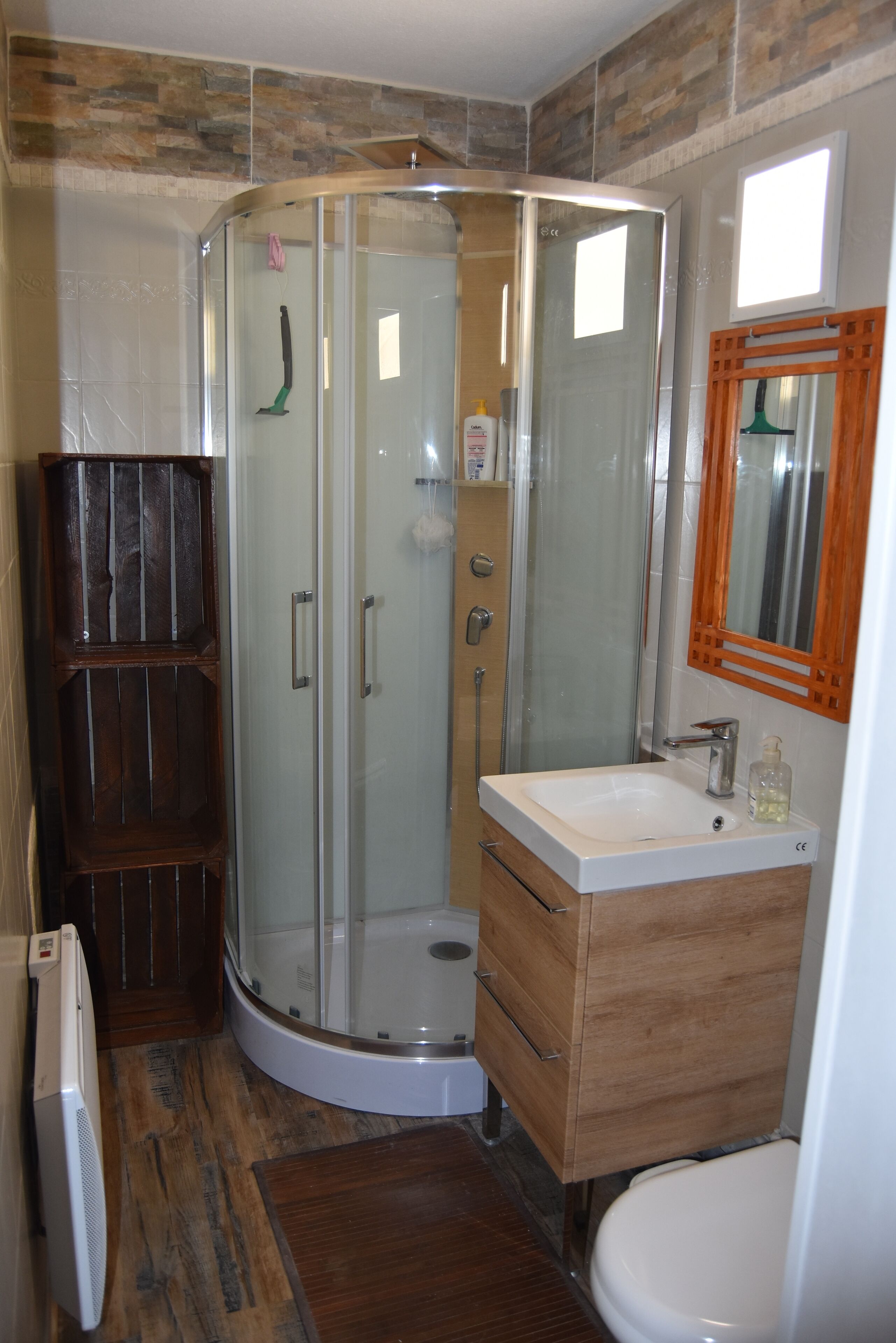 A bathroom with a glass-enclosed shower, wooden cabinets, and a white toilet.