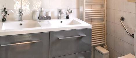 A modern bathroom with a double sink vanity, a toilet, and a towel rack.