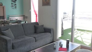 A living room with a grey sofa, a coffee table, and a dining area in the background.