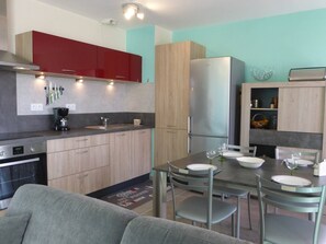 A modern kitchen with a dining area, featuring a refrigerator, stove, and various kitchen appliances.