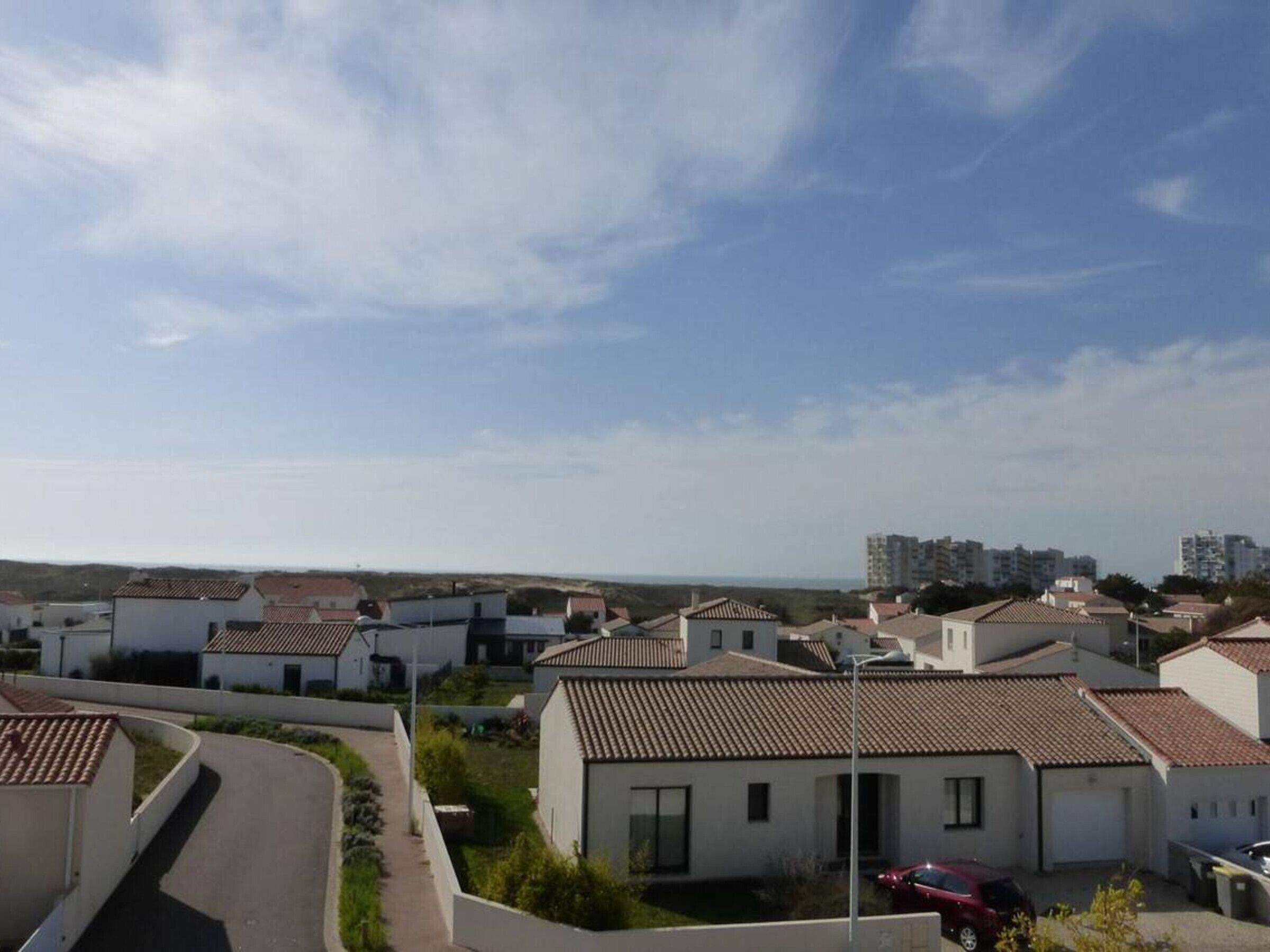 A residential area with houses featuring tiled roofs and a clear sky.