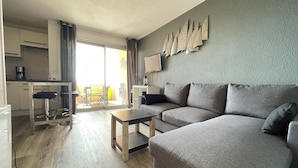Una sala de estar moderna con un sofá gris, una mesa de centro de madera y un comedor con un taburete de bar.