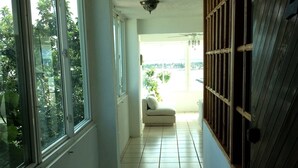 A corridor with tiled flooring, large windows, a ceiling fan, and a view of greenery outside. - El Encanto de Naturaleza y Romantic! Apartment 2 (Fajardo)