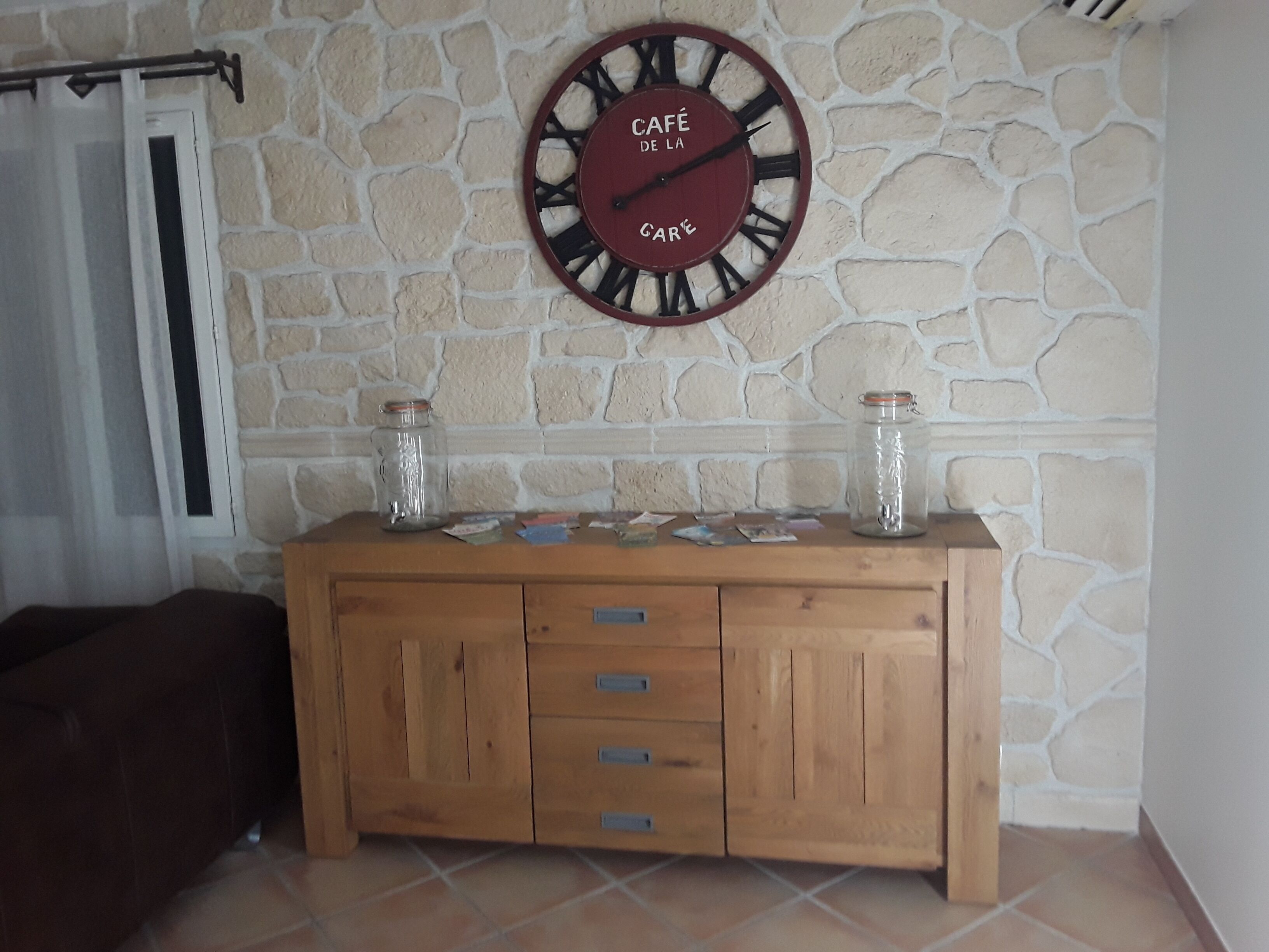 A stone wall with a wooden cabinet and a clock.