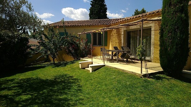Ein Haus mit einer Terrasse, einem Tisch und Stühlen.