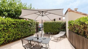 Une terrasse avec une table et des chaises, un grand parasol et une clôture en bois.