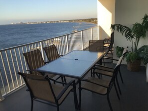 A balcony with a table and chairs overlooking the sea.