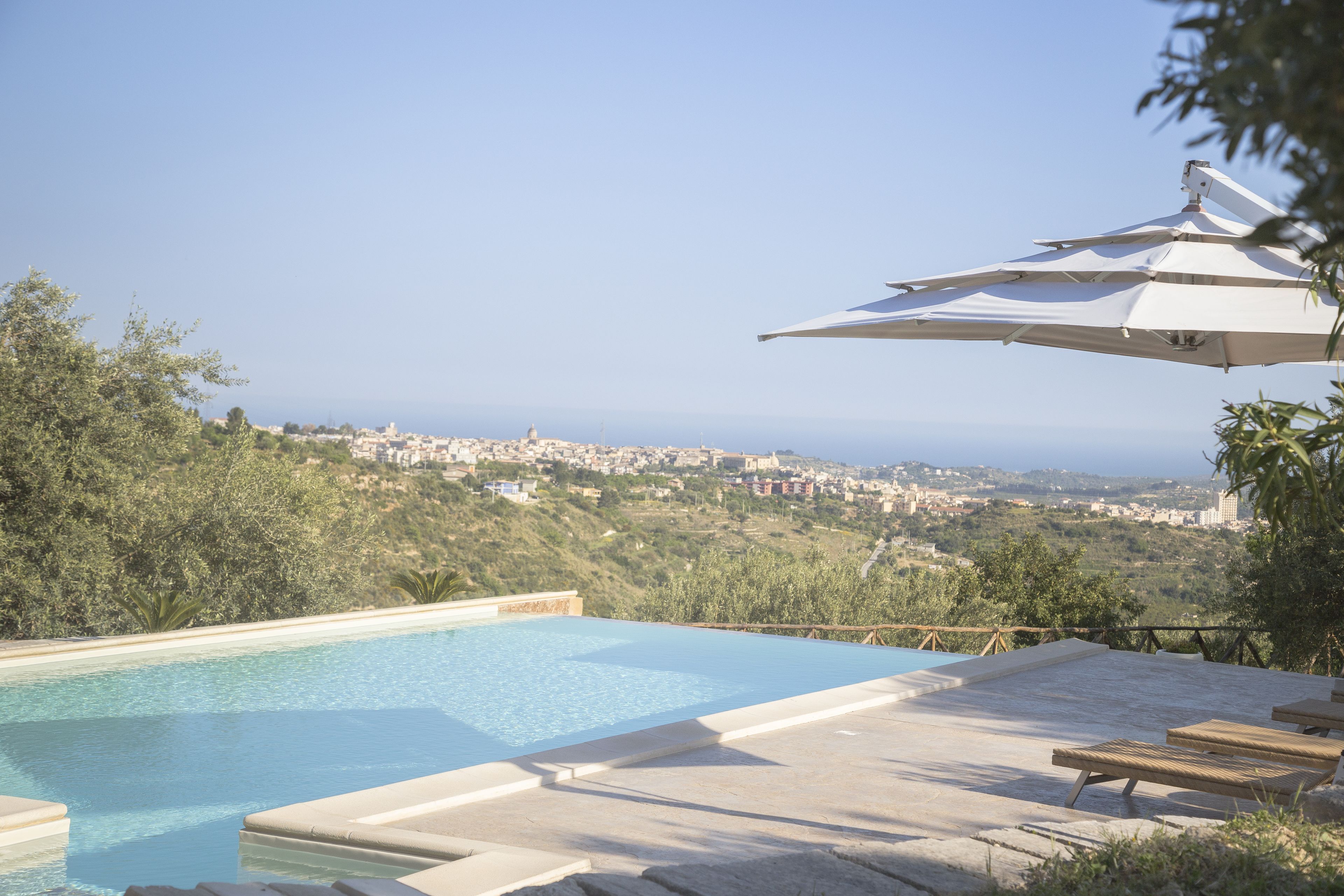 A swimming pool with a view of a town and hills in the background.