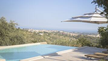 A swimming pool with a view of a town and hills in the background.