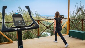Une personne fait de l'exercice avec des haltères sur un balcon donnant sur un paysage magnifique.