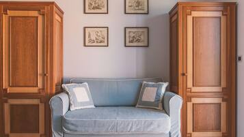 A room with a light blue sofa, two matching pillows, and three framed pictures on the wall. There are two wooden cabinets on either side of the sofa.