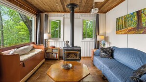 Una sala de estar acogedora con techo de madera, chimenea, sofá, una mesa de centro y estantería.