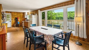 Una cabaña acogedora con comedor, cocina y vistas a un lago.