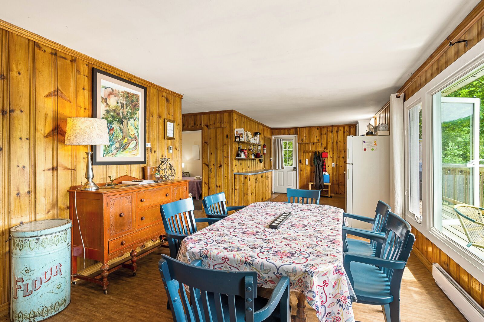 Un intérieur en bois comprenant une table à manger, des chaises, une commode et une fenêtre donnant sur un paysage agréable.