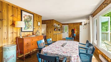 Un intérieur en bois comprenant une table à manger, des chaises, une commode et une fenêtre donnant sur un paysage agréable.