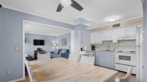 Una cocina moderna con armarios blancos, una mesa de comedor de madera y un ventilador de techo.