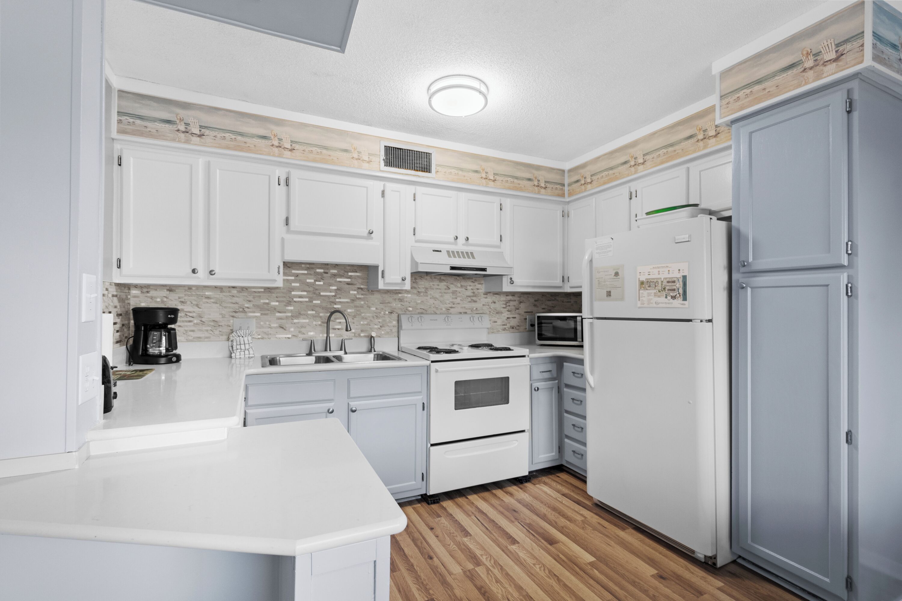 A modern kitchen with white cabinets, a microwave, a stove, and a refrigerator.