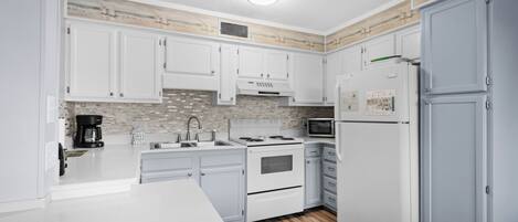 A modern kitchen with white cabinets, a microwave, a stove, and a refrigerator.