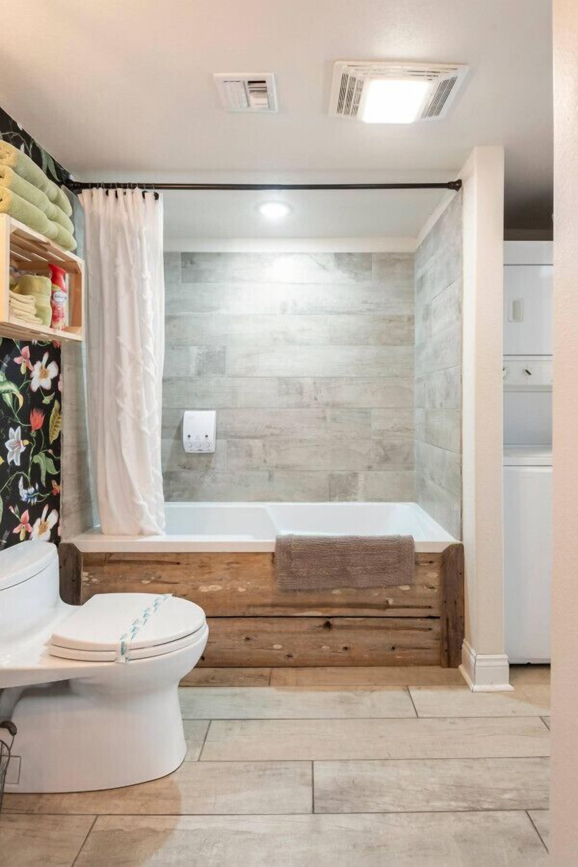 A bathroom with a bathtub, toilet, and shower curtain.